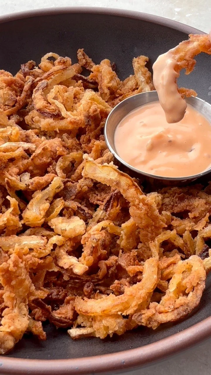 Plate of crispy onion strings garnished and ready to serve
