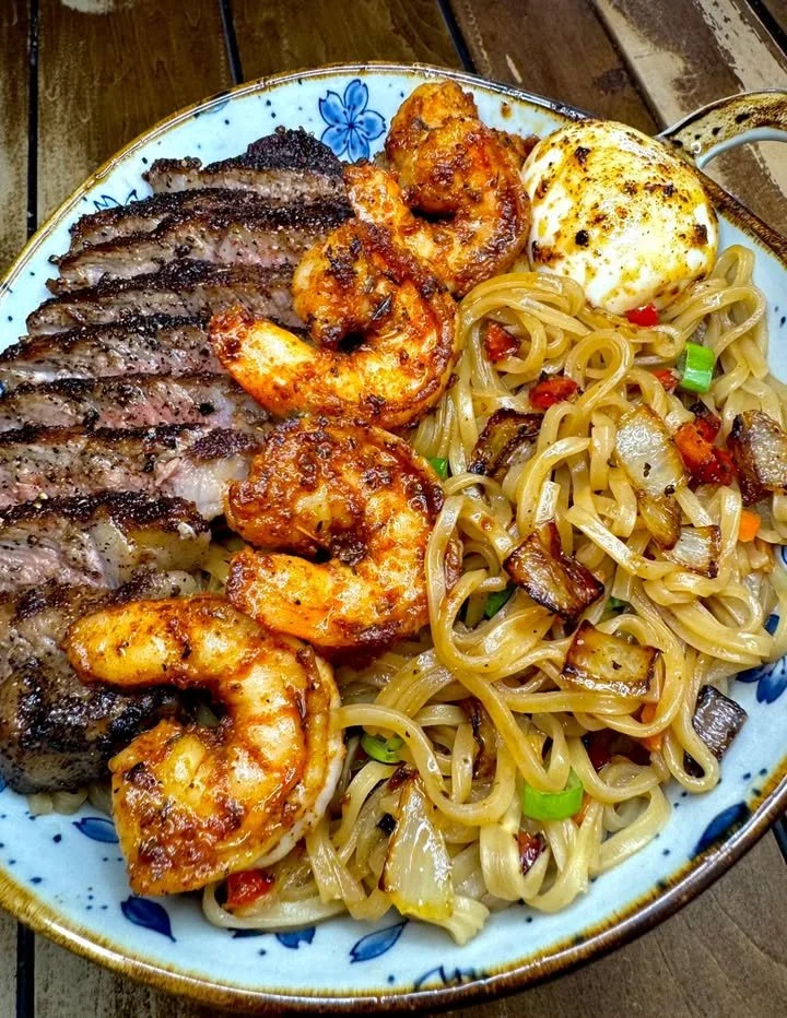 Delicious steak and shrimp noodles in a bowl with fresh vegetables